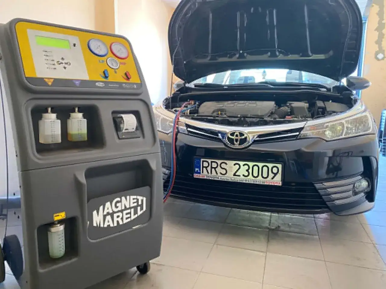 Stacja do obsługi klimatyzacji samochodowej Magneti Marelli obok czarnej Toyoty. Sprawdzanie koszt nabicia klimatyzacji.