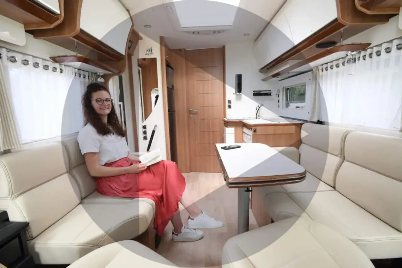 Jeune femme lisant dans le salon face &agrave; face d'un camping-car confortable.