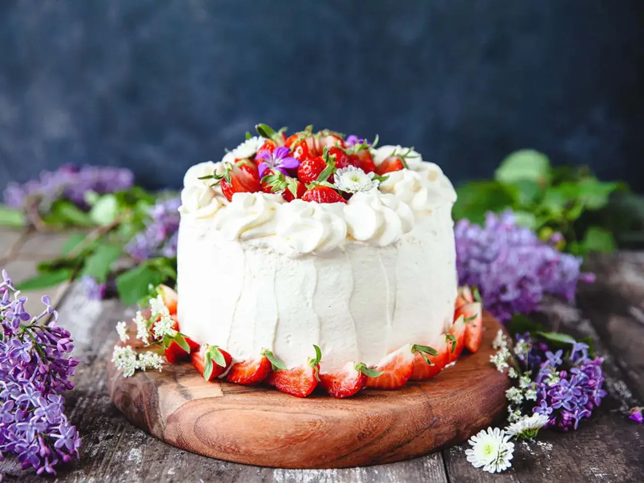 En vacker vegansk jordgubbstårta med fluffig grädde, färska jordgubbar och lila syrener.