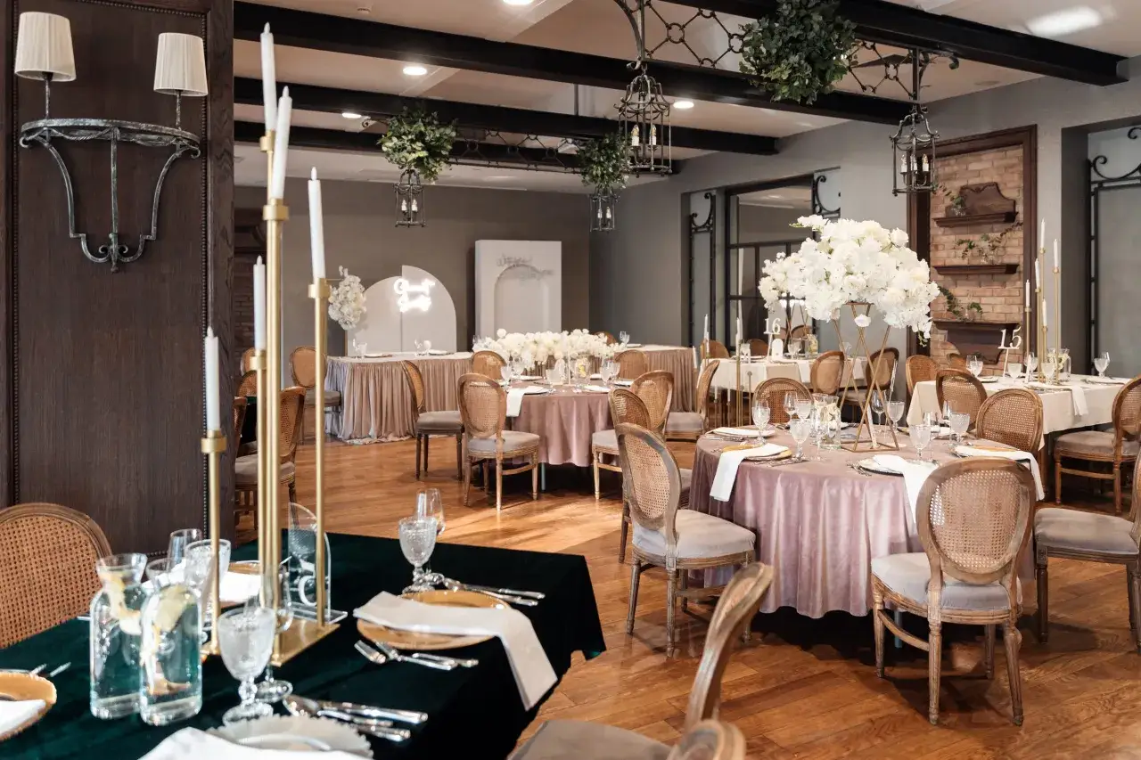 Elegancka sala weselna z okrągłymi stołami, świecami i kwiatami. Czy ślub w lipcu przesądy mają znaczenie przy takiej oprawie?