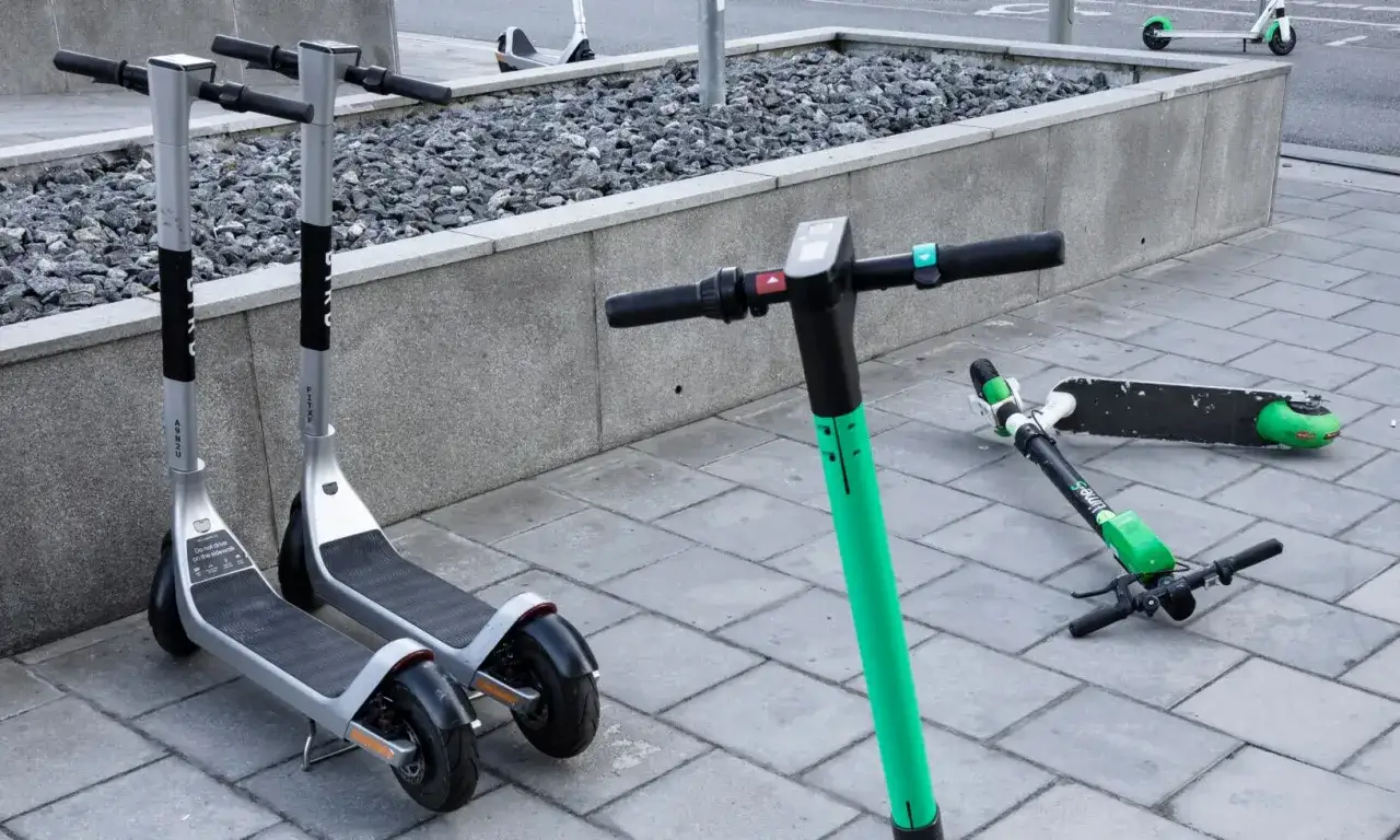 Flera elsparkcyklar st&aring;r uppst&auml;llda och en ligger p&aring; marken. T&auml;nk p&aring; elsparkcykel regler f&ouml;r s&auml;ker f&auml;rd.