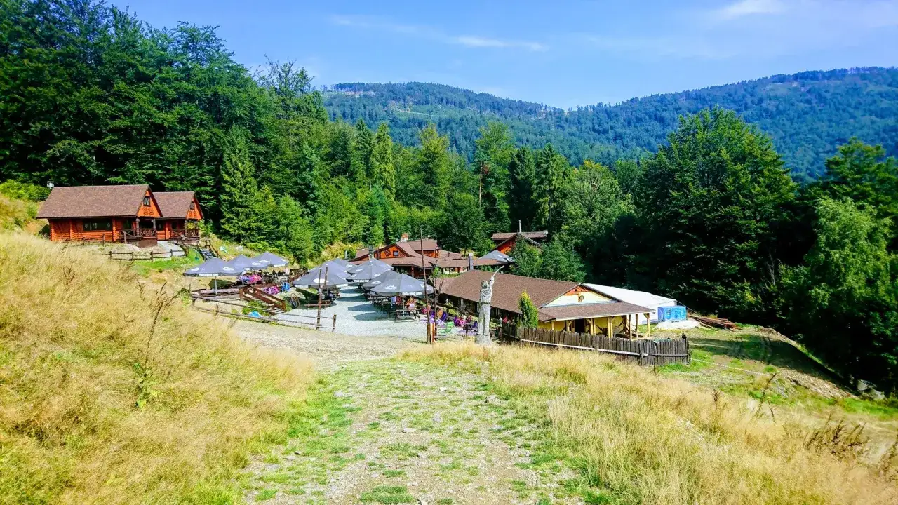 Drewniane domki i budynki zadaszone parasolami tworzą przytulną atmosferę, niczym w chacie wuja Toma, otoczone bujną zielenią g&oacute;r.