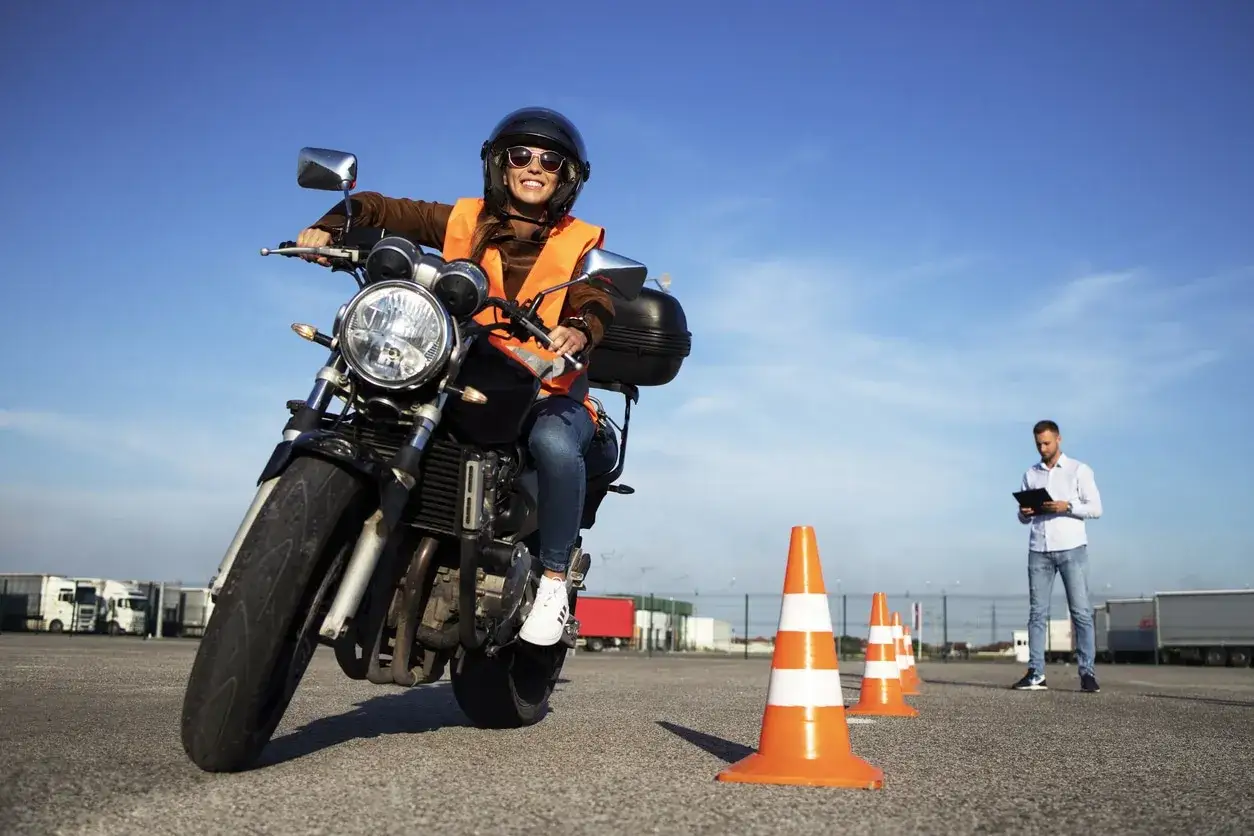 Joven sonriente practica para su carnet moto 18 años, con instructor observando.