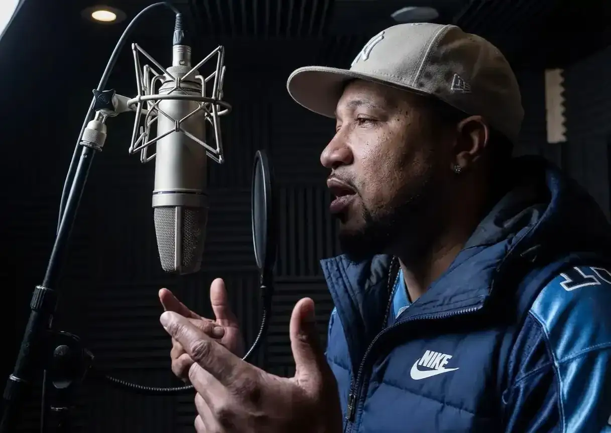 Un homme apprend à rapper dans un studio d'enregistrement, parlant dans un microphone professionnel.