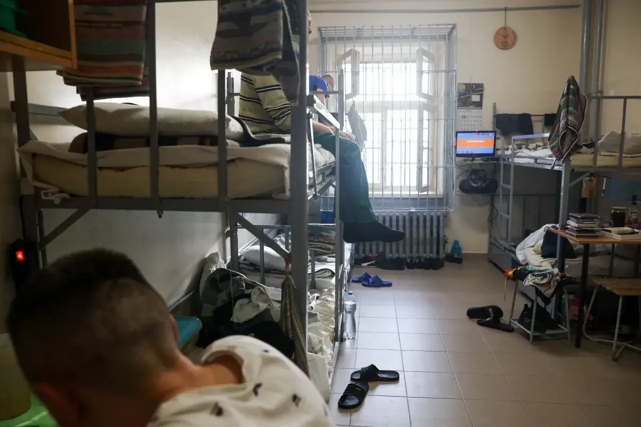 Wspomnienie z zakładu karnego Montelupich: więźniowie w celach, łóżka piętrowe, kraty w oknach.