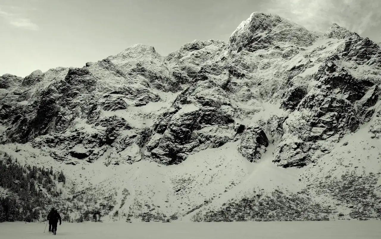 Majestatyczne Tatry w marcu. Samotny turysta przemierza ośnieżone szlaki, podziwiając surowe piękno gór.