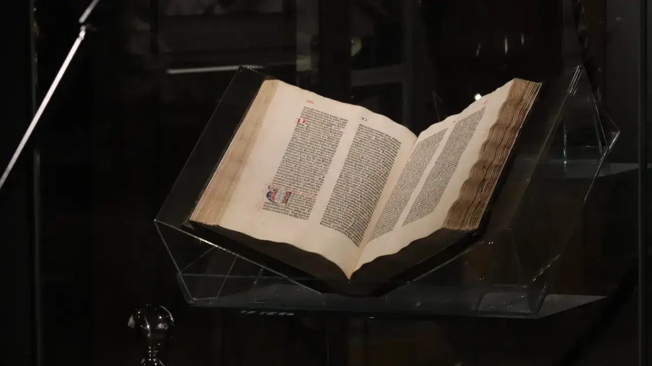 Otwarta biblia gutenberga pelplin, prezentowana w szklanej gablocie.