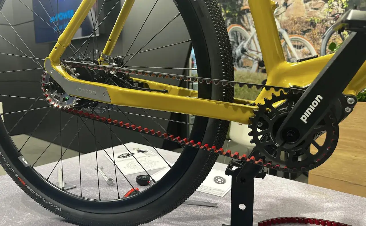 Close-up of a yellow belt drive mountain bike's rear wheel and drivetrain, showcasing the Pinion gearbox and Gates Carbon Drive belt.