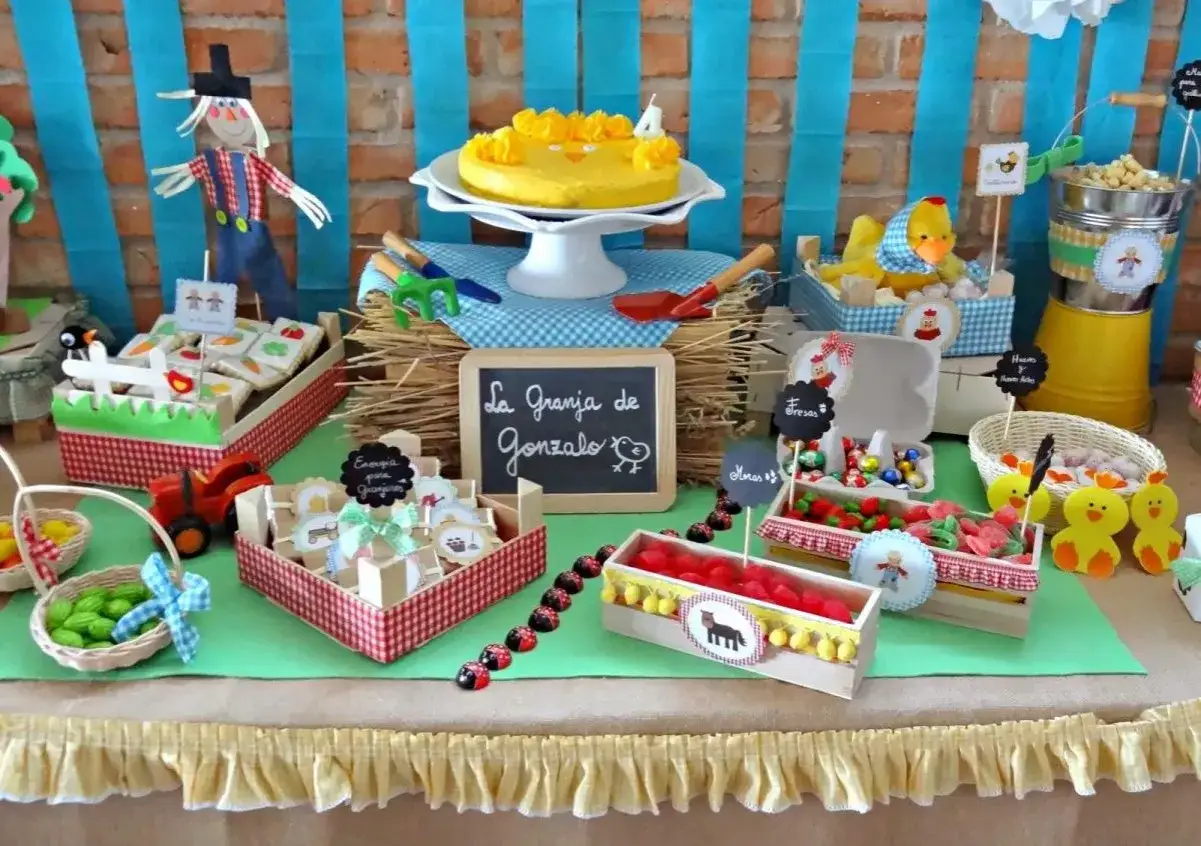 Una mesa de chuches casera temática de granja con un espantapájaros, pastel de pollo, dulces y decoraciones rústicas.