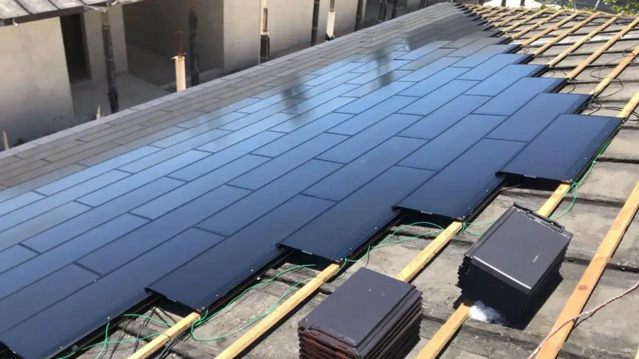 Instalación de placas solares en un tejado, optimizando el rendimiento energético. Se ven las piezas oscuras y los cables verdes.