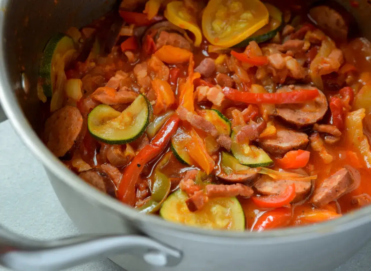 Pyszny bigos z cukinii z kiełbasą i papryką, gotowany w garnku.