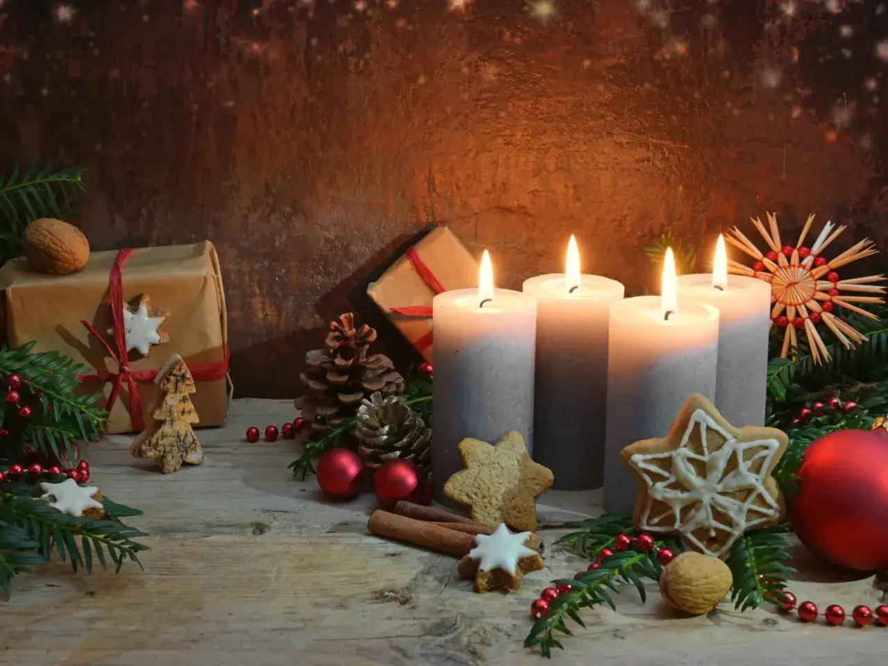 Vier Kerzen leuchten auf einem Adventskranz, ein Symbol für die Hoffnung im Christentum. Tannenzweige, Zimtstangen und Sterne schmücken die Szene.