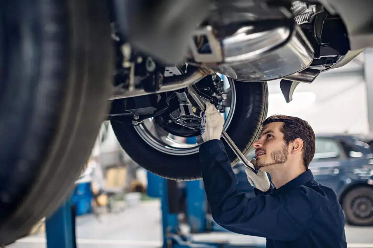 Mechanik w białych rękawiczkach naprawia podwozie samochodu, by uniknąć problemów z zatartym silnikiem.