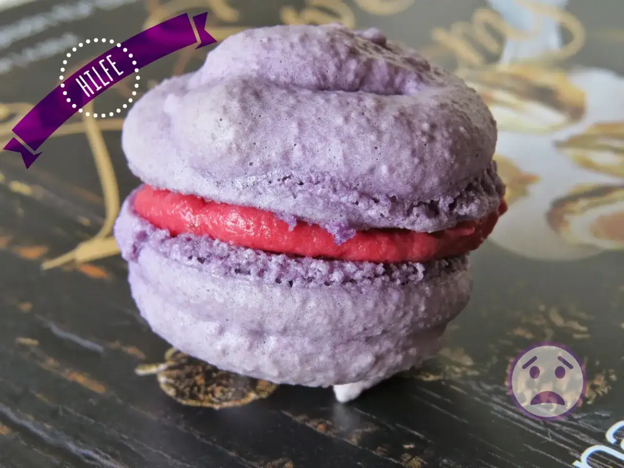 Ein lila Macaron mit roter F&uuml;llung, das Ergebnis eines Macarons rezept. Hilf mir, es zu essen!