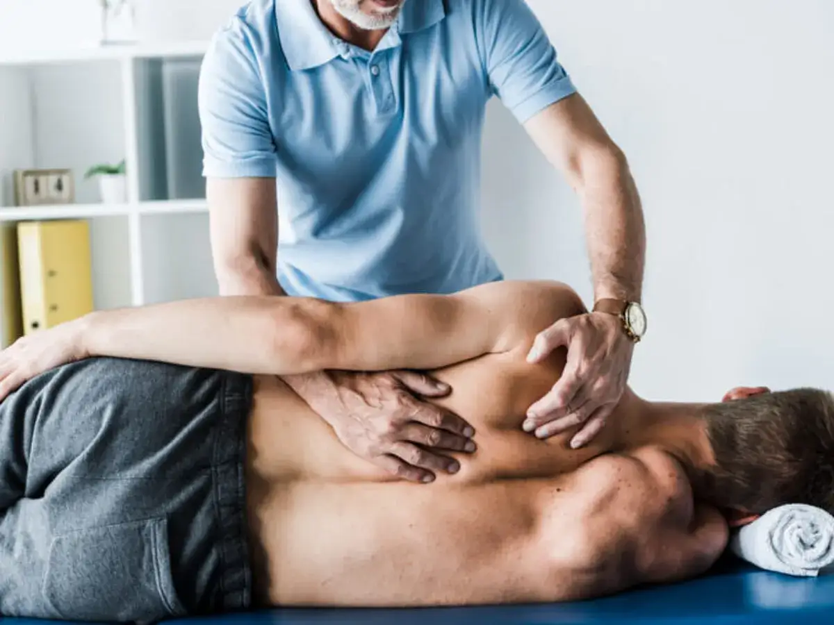 Fizjoterapeuta wykonuje masaż pleców, pomagając w rehabilitacji po złamaniu kręgosłupa lędźwiowego.