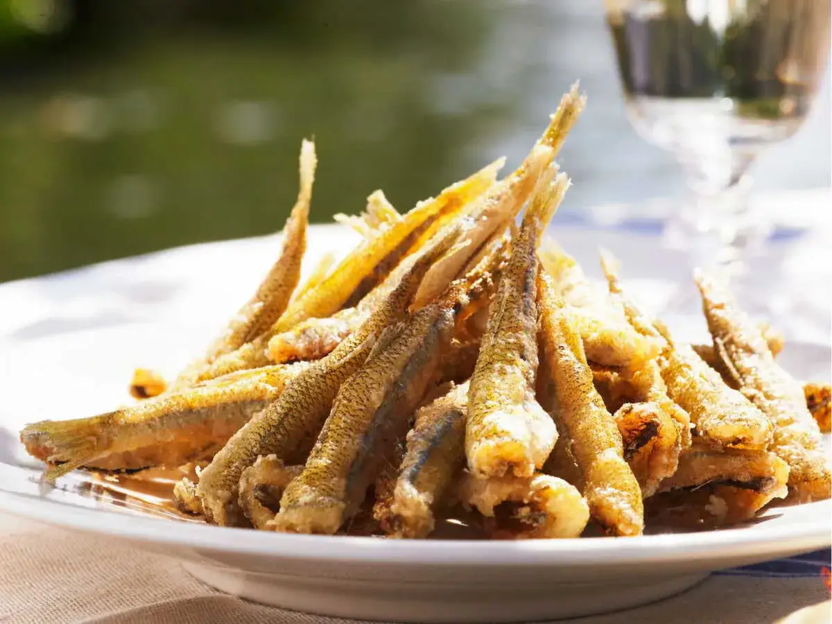 Une assiette de friture de poisson dor&eacute;e et croustillante, pr&ecirc;te &agrave; &ecirc;tre d&eacute;gust&eacute;e au bord de l'eau.