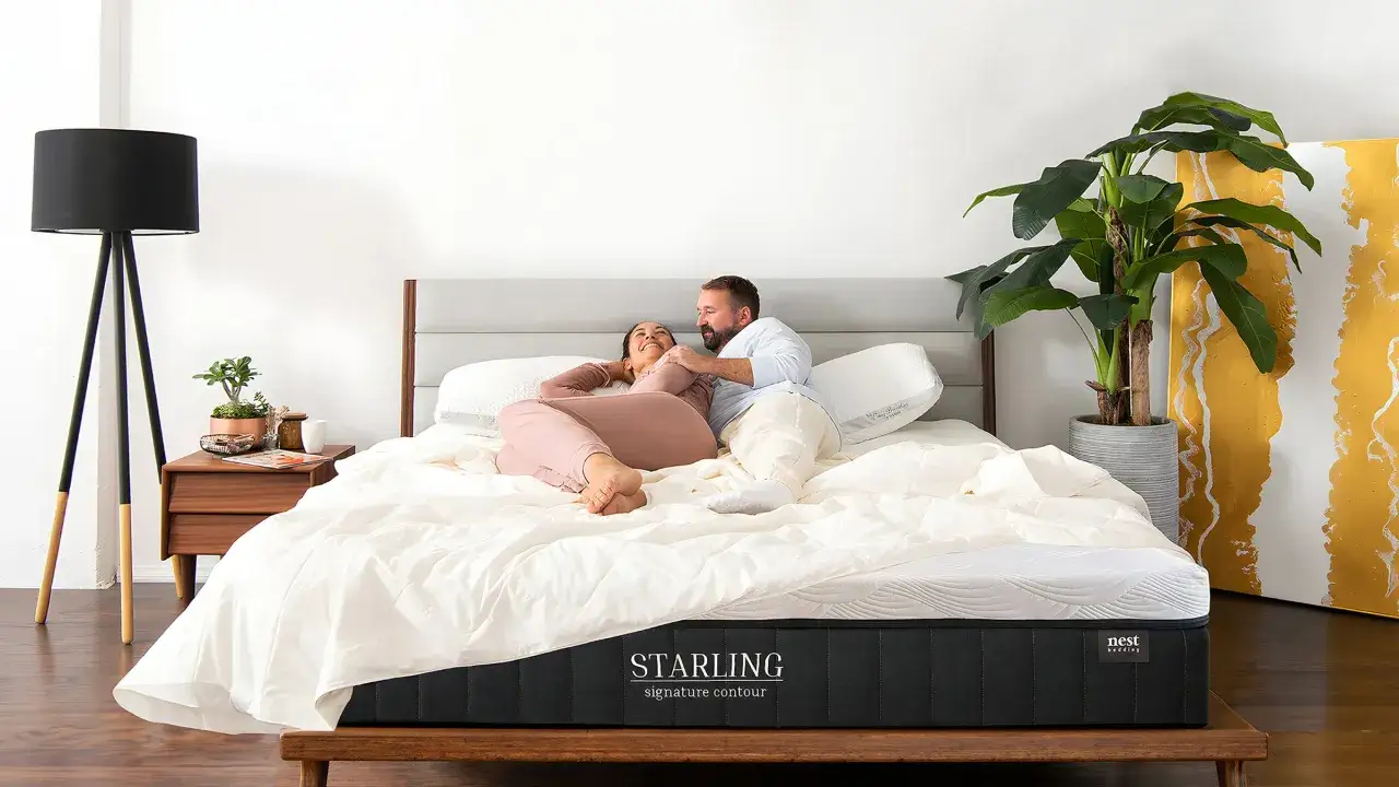 A couple smiles on a luxurious bed, proving that even an uncomfy bed can be a dream with the right mattress.