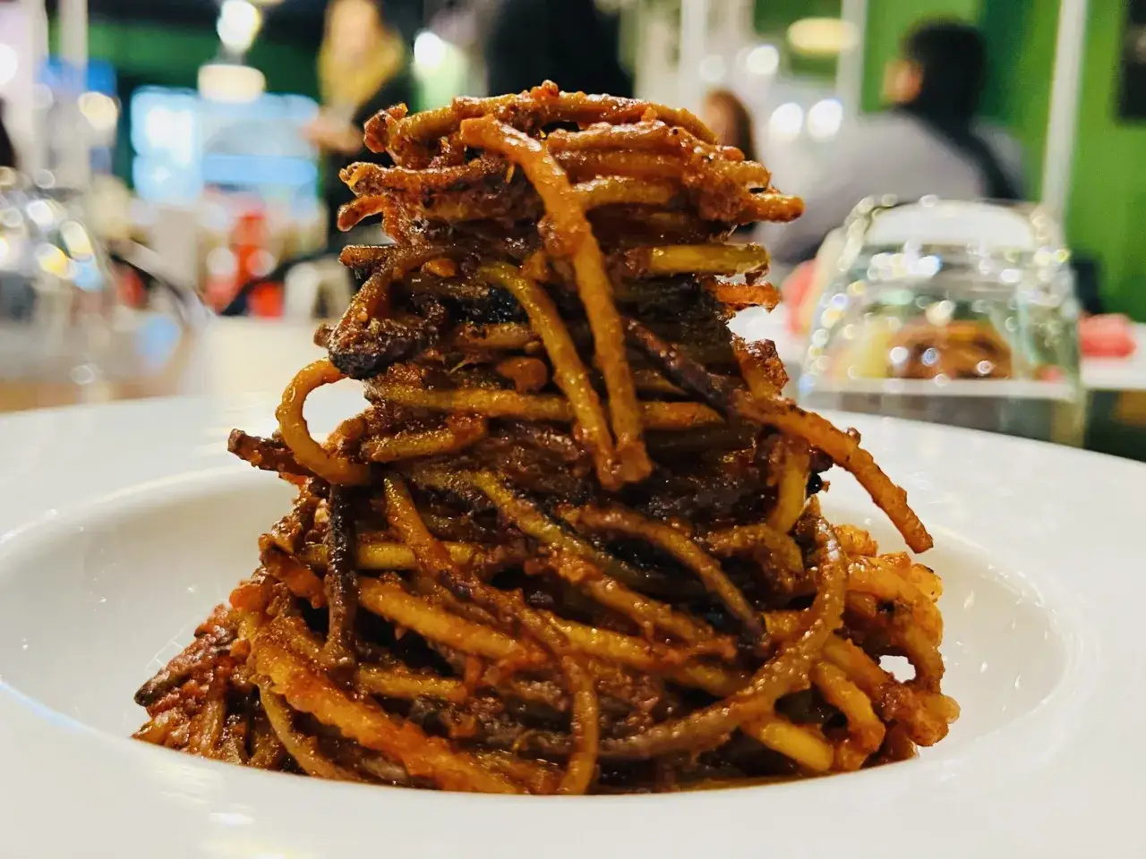 Un plat de spaghetti all'assassina, croustillants et enrob&eacute;s d'une sauce rouge intense, servi dans une assiette blanche.