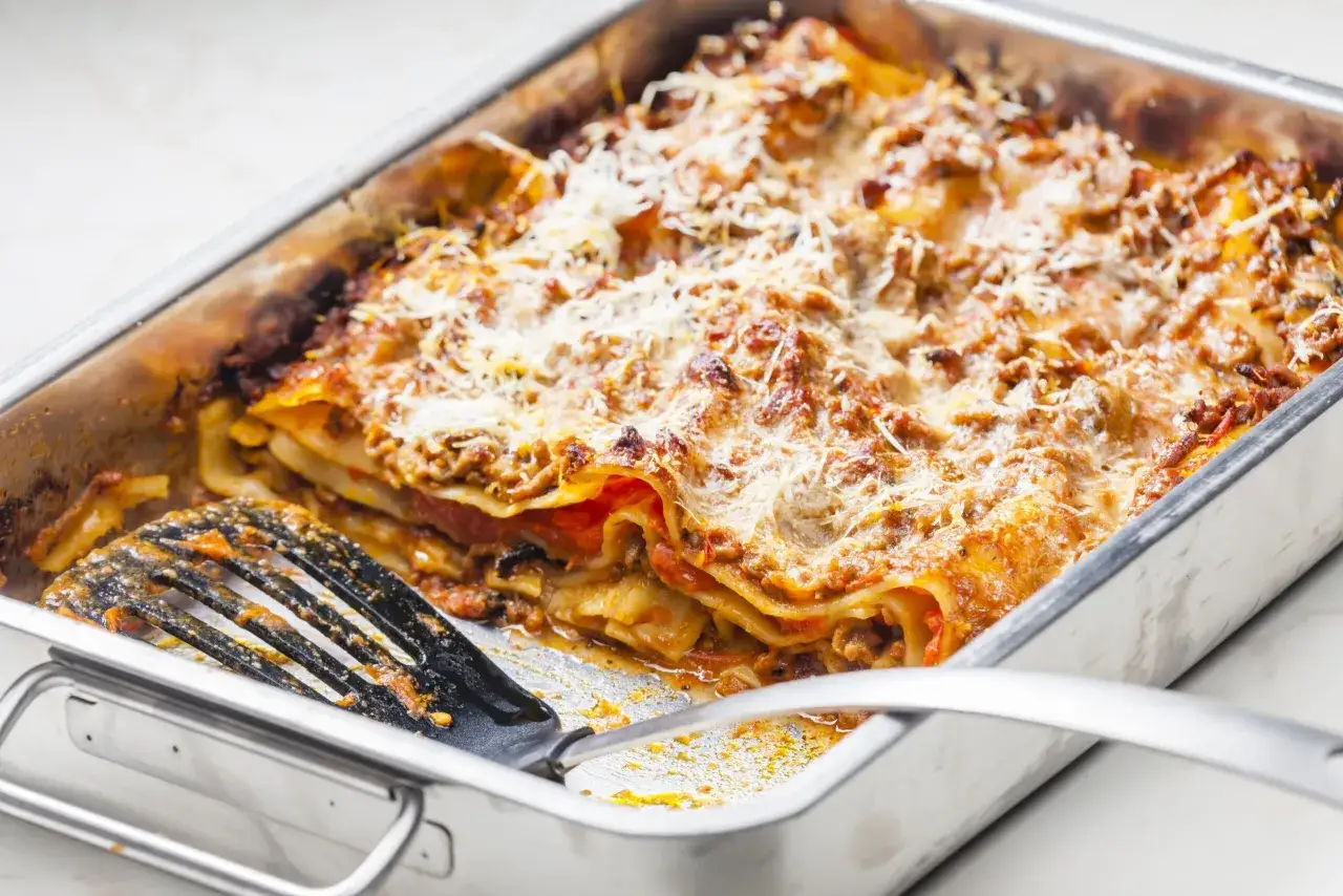 Lasagnes dor&eacute;es et gratin&eacute;es dans un plat, une spatule en train de servir une portion. Parfait pour une quantit&eacute; lasagne pour 12 personnes.