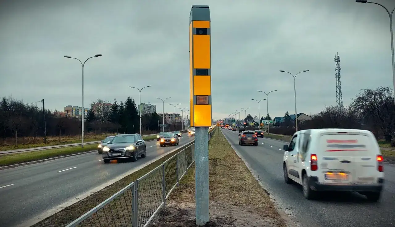 Fotoradar na drodze, który może wystawić mandat z fotoradaru na inną osobę. Samochody jadą w pochmurny dzień.