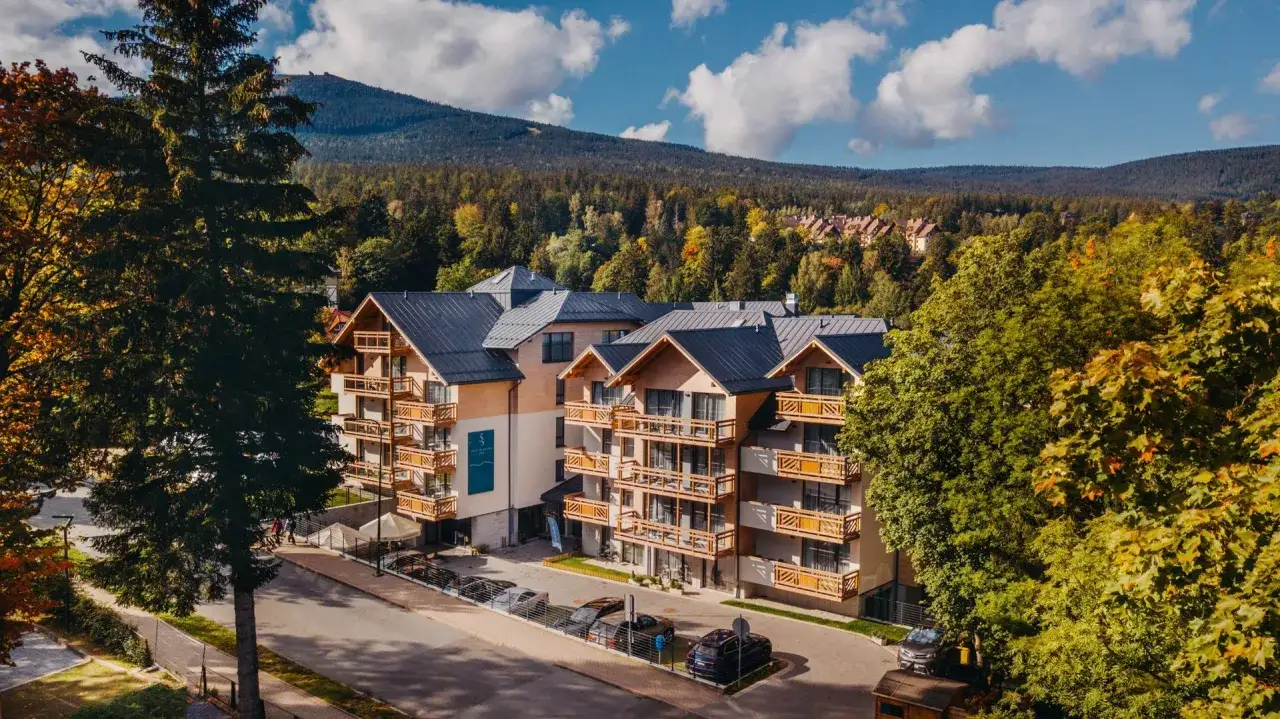 Nowoczesny hotel z widokiem na góry, idealny na noclegi Szklarska Poręba. Otoczony zielenią, z balkonami i parkingiem.