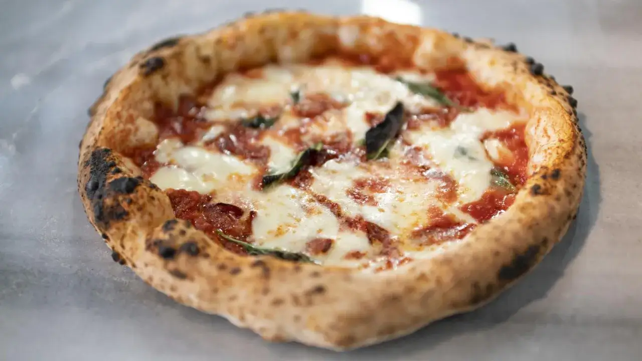 Pizza casera con bordes dorados, queso derretido y albahaca. Perfecta para hacer con harina 00 Mercadona.