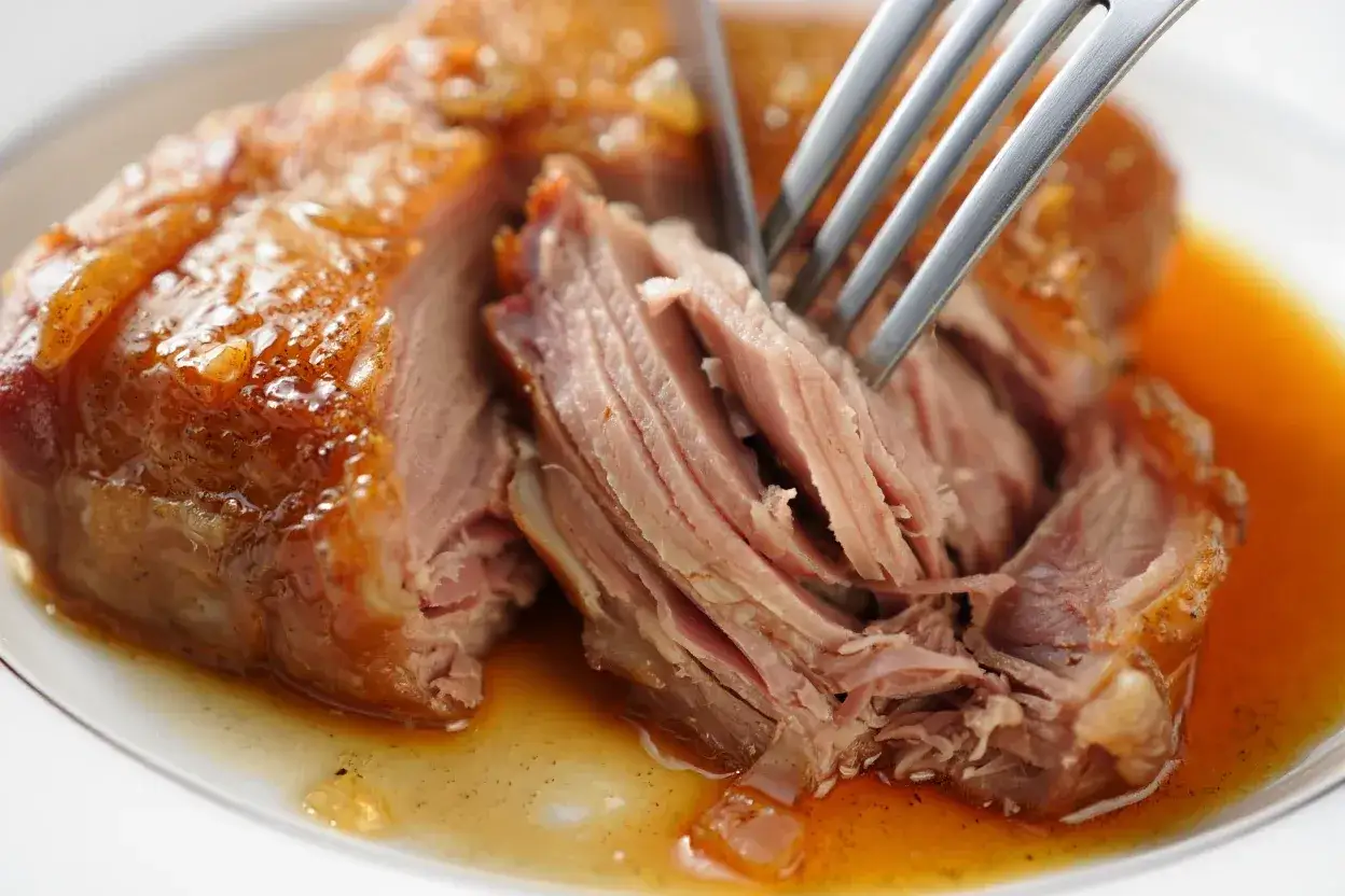 Une rouelle de porc juteuse, effilochée à la fourchette, baignant dans sa sauce dorée.