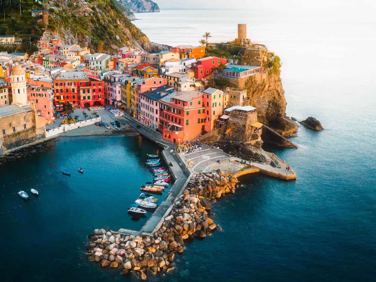 Vernazza, one of the best towns to stay in Cinque Terre, with colorful buildings cascading down to a blue harbor filled with boats.