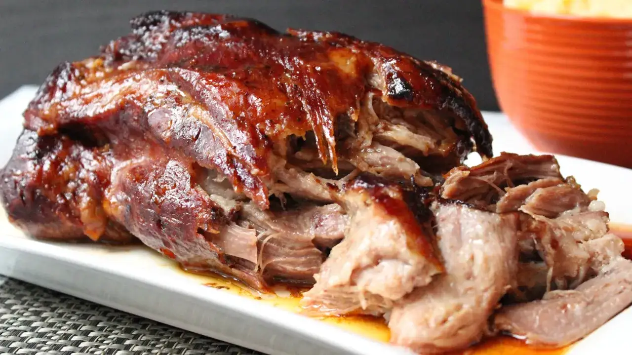 Rouelle de porc au barbecue, tendre et juteuse, prête à être dégustée. La viande effilochée révèle sa cuisson parfaite.