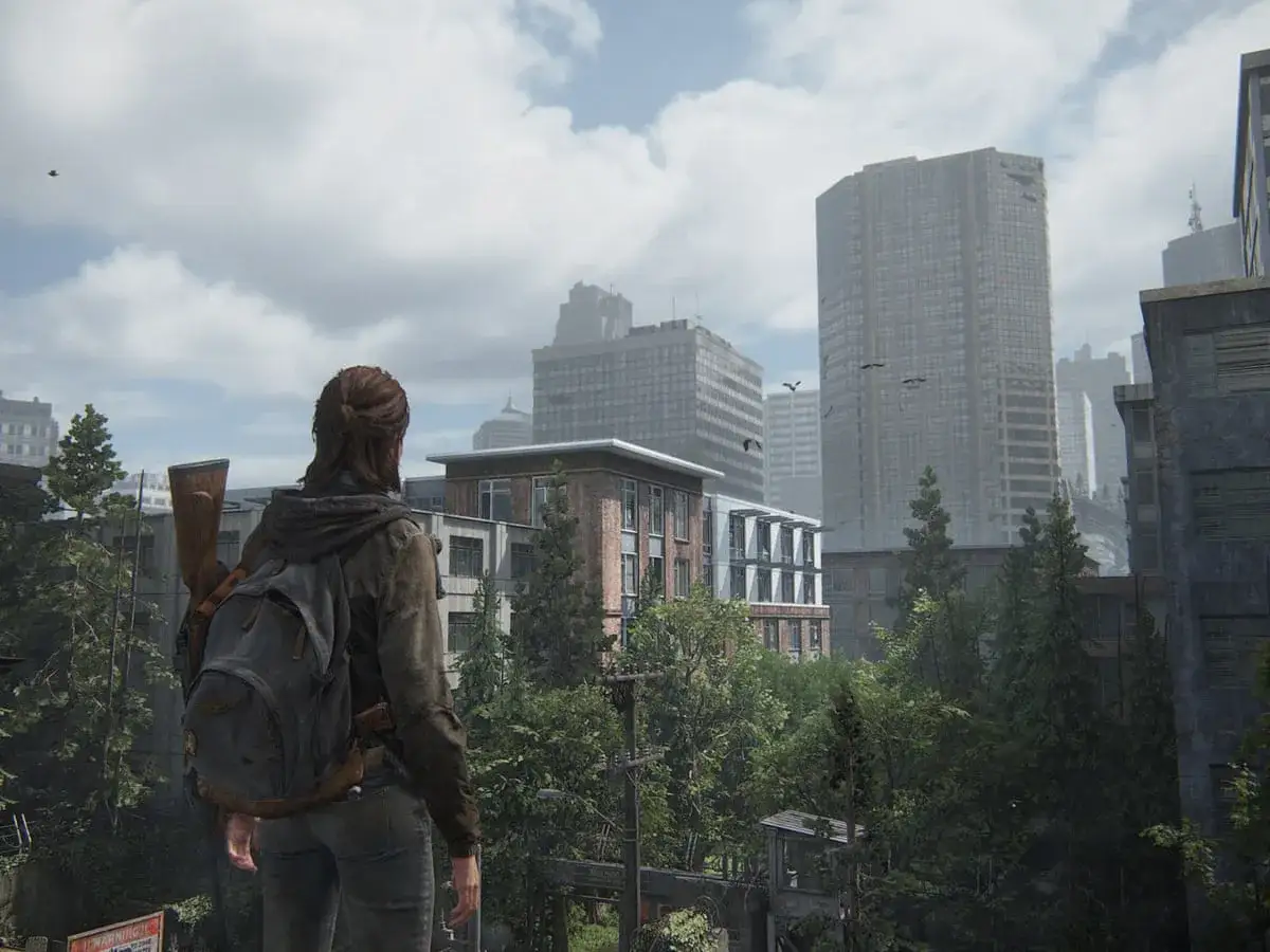 Ellie, con su mochila y rifle, observa una ciudad post-apocalíptica en The Last of Us 2 Remastered.