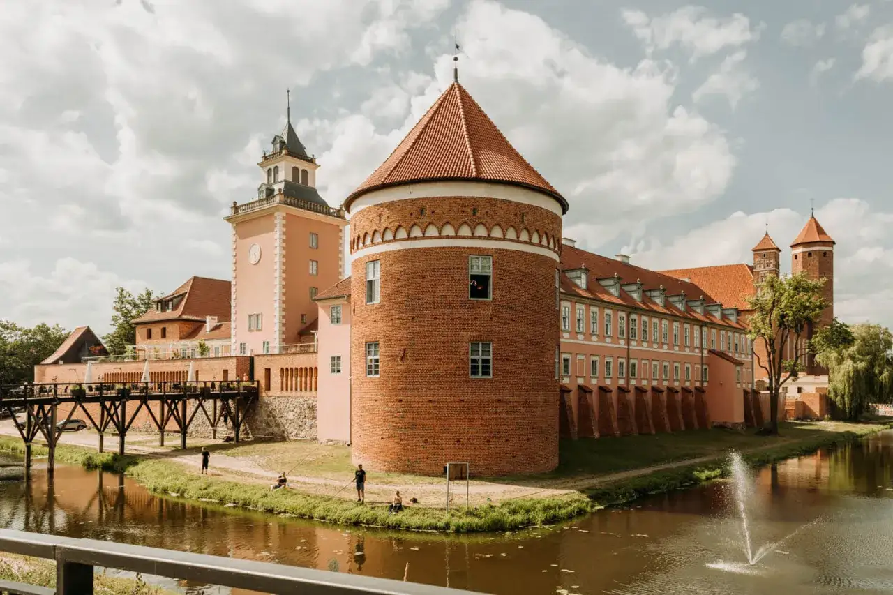 Zamek w Lidzbarku Warmińskim, z charakterystyczną ceglaną wieżą i różową fasadą, to jedna z głównych atrakcji regionu.