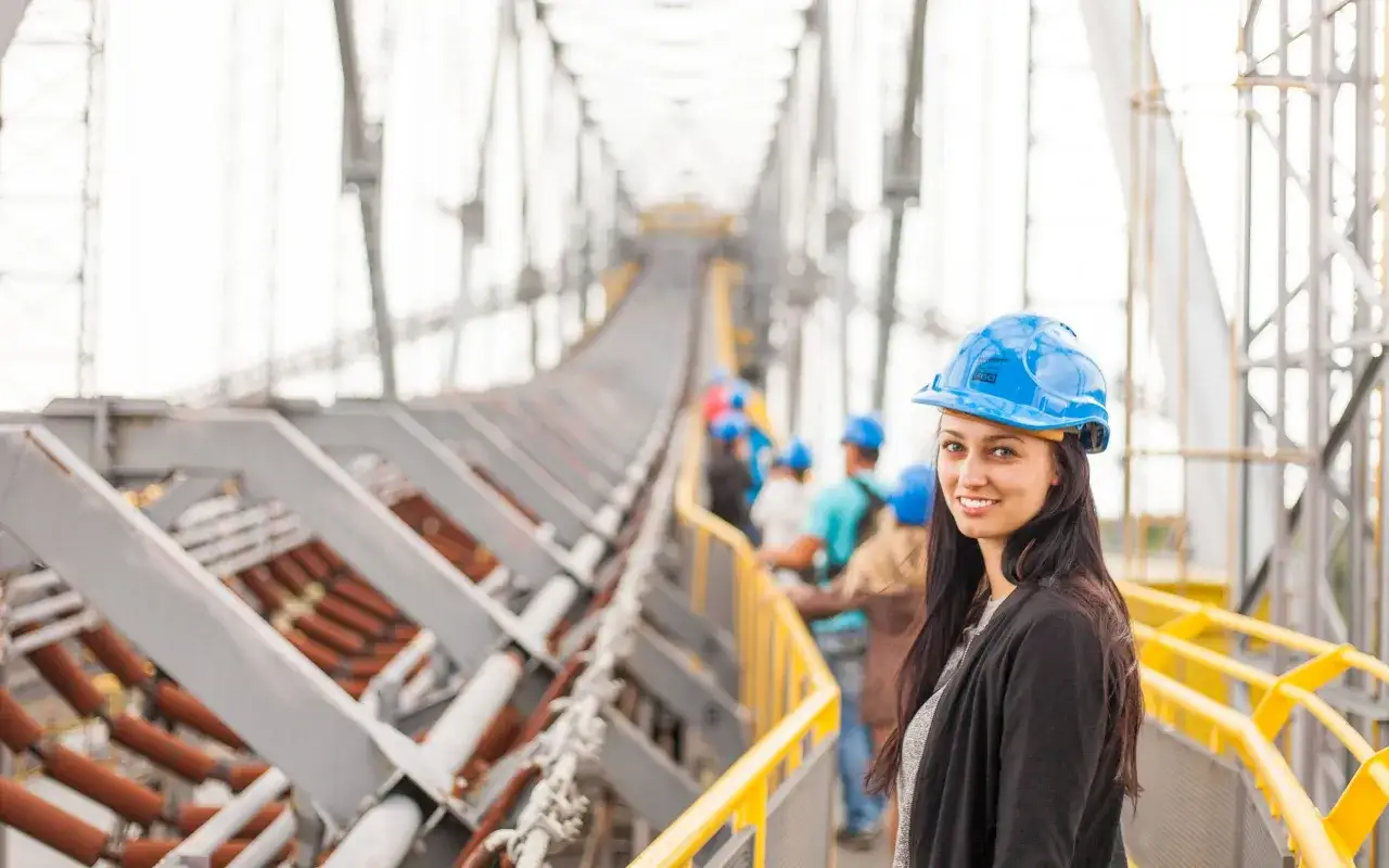 Donna con casco blu in un impianto industriale. Chissà quando arriva il pagamento infortunio INAIL per i lavoratori.