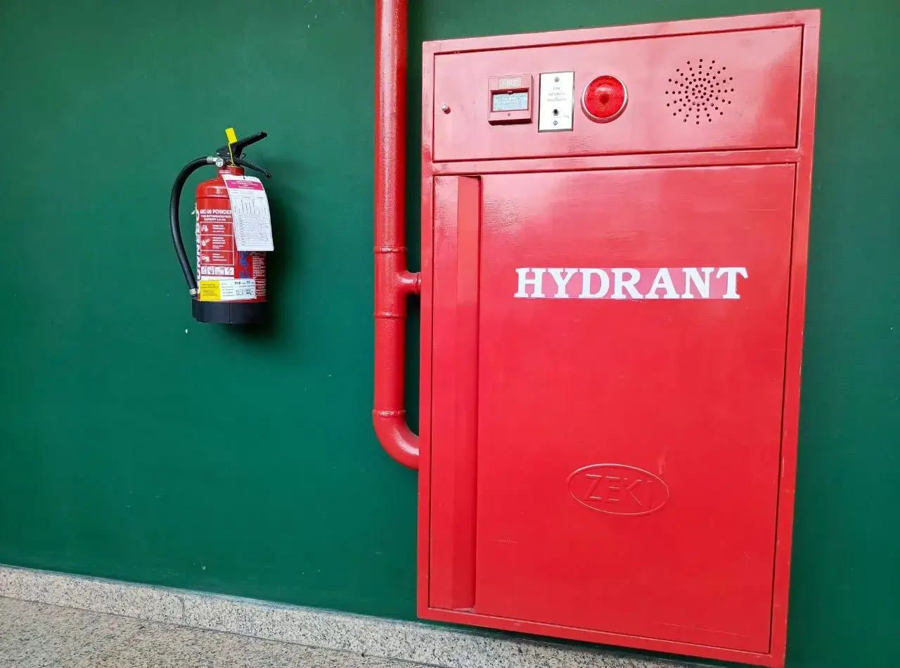 Czerwona szafka z napisem HYDRANT i gaśnica wisząca obok. R&oacute;żne rodzaje hydrant&oacute;w i sprzętu przeciwpożarowego są kluczowe dla bezpieczeństwa.