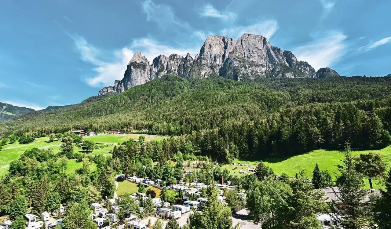Malowniczy widok na camping Seiser Alm z kamperami i przyczepami kempingowymi u podnóża majestatycznych gór.