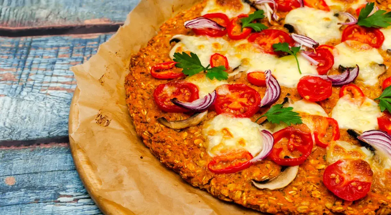 Pizza z niskim indeksem glikemicznym na chrupiącym spodzie z płatków owsianych, z pomidorami, cebulą i mozzarellą.