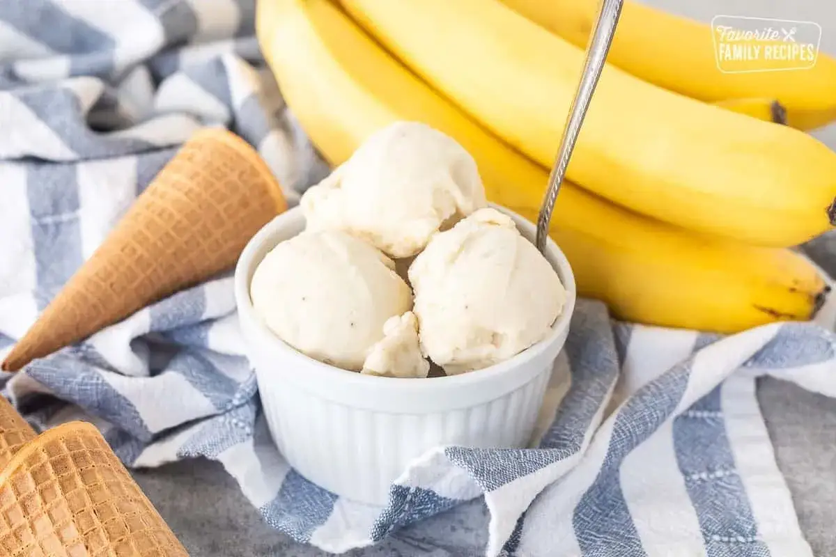 Gelato cremoso servito in una ciotola, con banane mature sullo sfondo. Un'idea per sostituire lo zucchero con la banana per un dolce più sano.