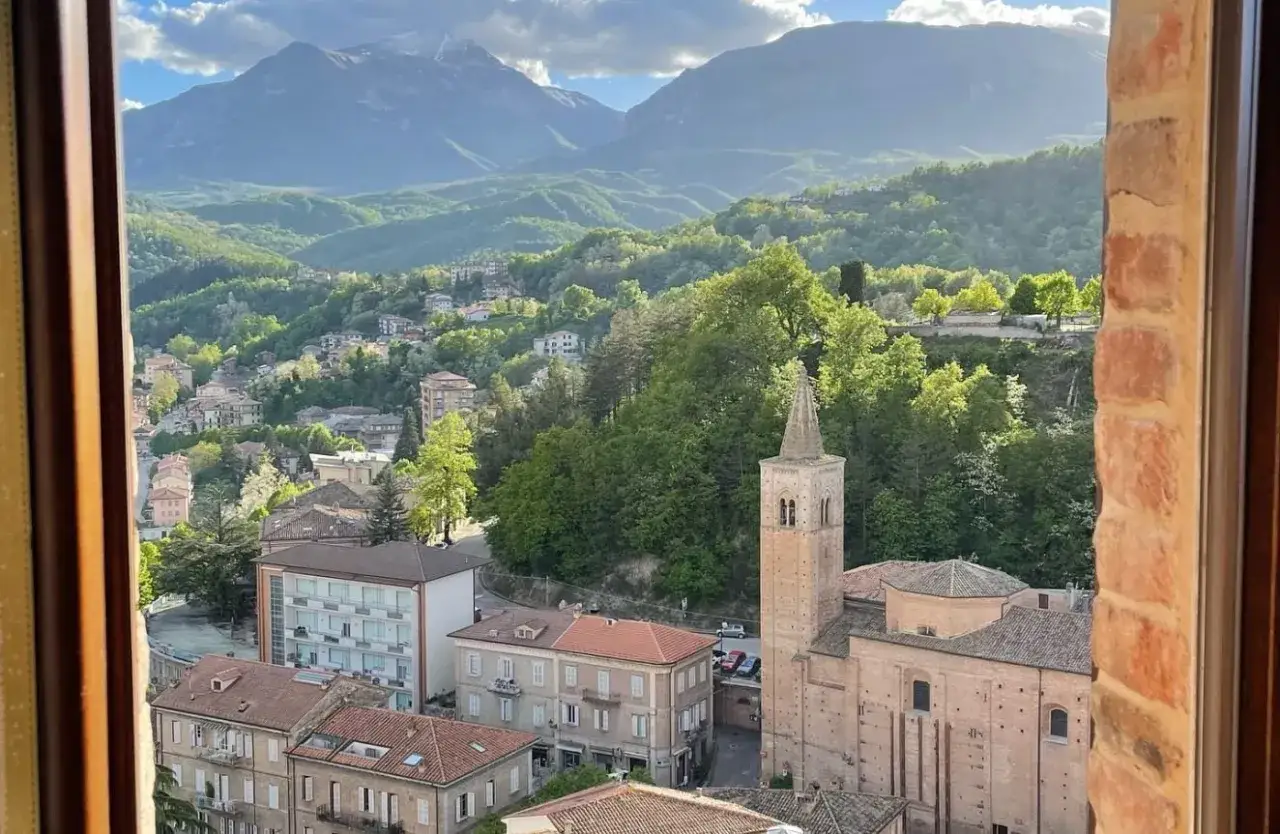 Vista di un borgo italiano con campanile e montagne sullo sfondo. Perfetto per scoprire cosa fare a novembre in Italia, tra borghi e natura.