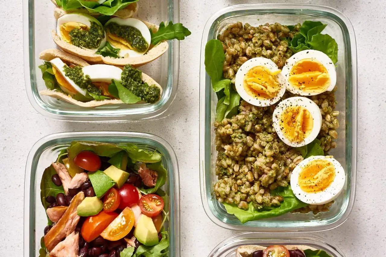 Vier Beh&auml;lter mit gesunden Mahlzeiten, die helfen, 1500 Kalorien am Tag zu erreichen: gef&uuml;llte Pitabrote mit Ei, Getreidesalat mit Ei und ein Salat mit Lachs und Bohnen.