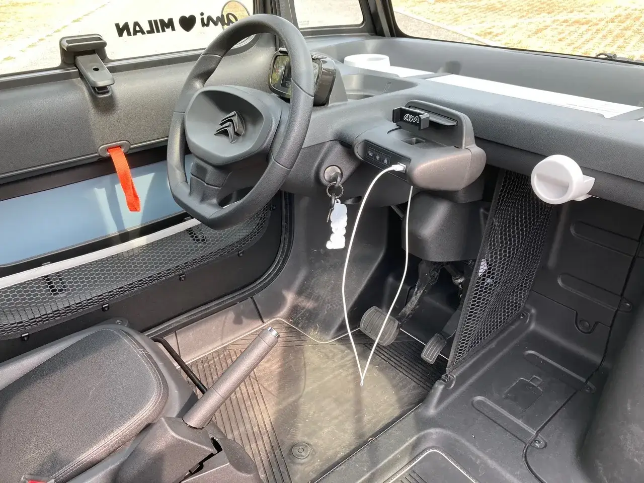Interno Citroen Ami: volante, cruscotto con supporto per telefono e presa USB, freno a mano. La sicurezza &egrave; garantita da un design compatto e funzionale.