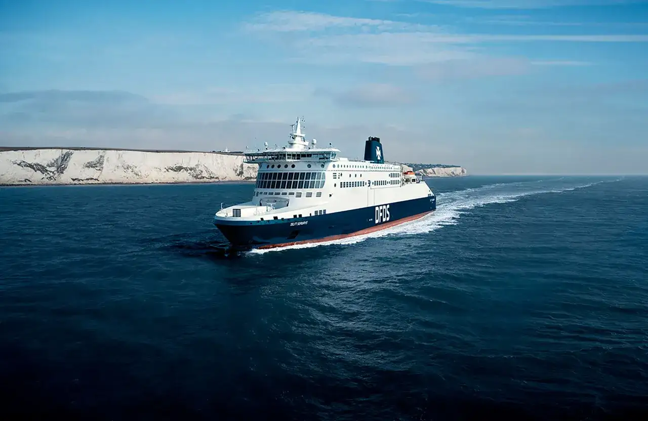 Duży prom DFDS płynie po wzburzonym morzu w kierunku białych klifów. To podróż z Dunkierki.