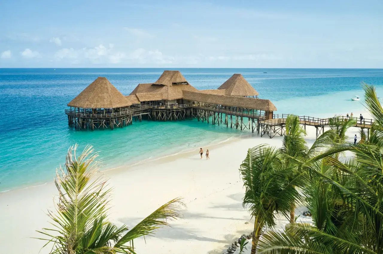 Piękna plaża na Zanzibarze z drewnianym molo i palmami. Idealne miejsce, by pomyśleć, co zabrać na Zanzibar.