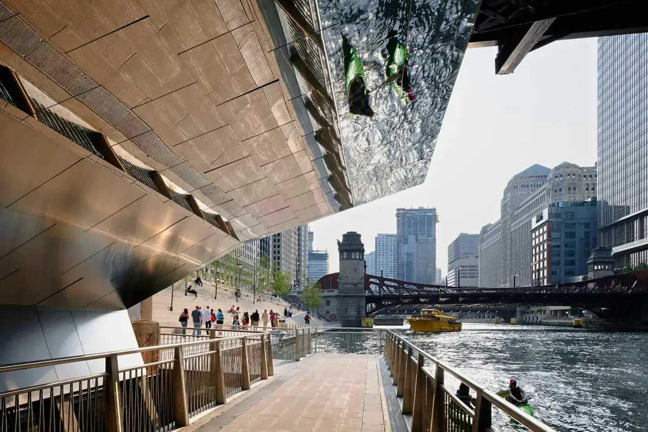 Paseo por el río Chicago, ideal para saber qué ver en Chicago en 3 días. Gente pasea, un bote amarillo navega y se aprecian edificios icónicos.