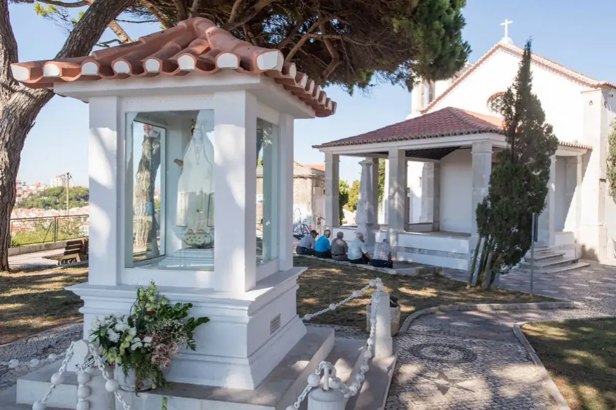 Heilige Maria von Nossa Senhora do Monte in einer Kapelle, Gläubige beten davor.
