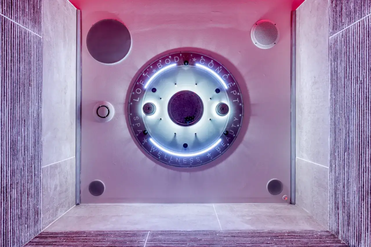 Une cabine de douche sensorielle futuriste avec des lumi&egrave;res bleues et roses, des jets d'eau et des haut-parleurs int&eacute;gr&eacute;s pour une exp&eacute;rience de bien-&ecirc;tre ultime.
