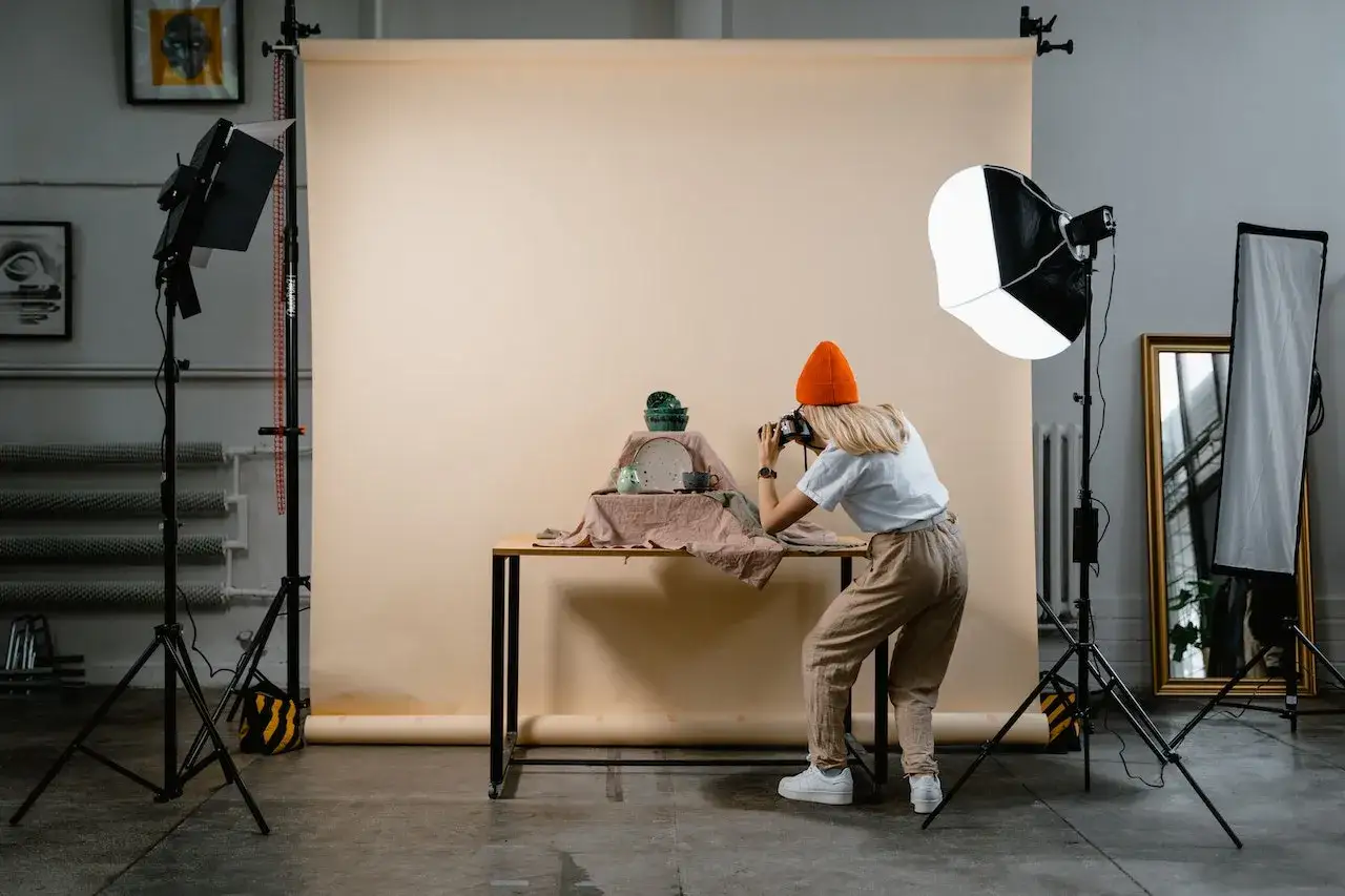 Photographe en action pour une photographie de produits, capturant des céramiques sur une table.