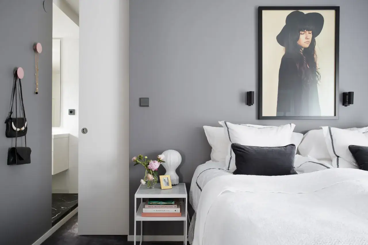 Elegante camera da letto con letto grigio chiaro abbinamenti perfetti: cuscini scuri, quadro artistico e dettagli chic.