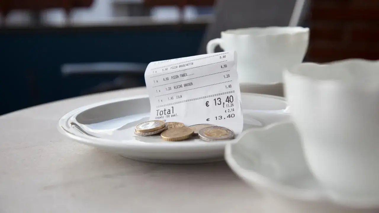 Rechnung mit M&uuml;nzen auf einem Teller, bereit f&uuml;r das Trinkgeld in Sardinien.