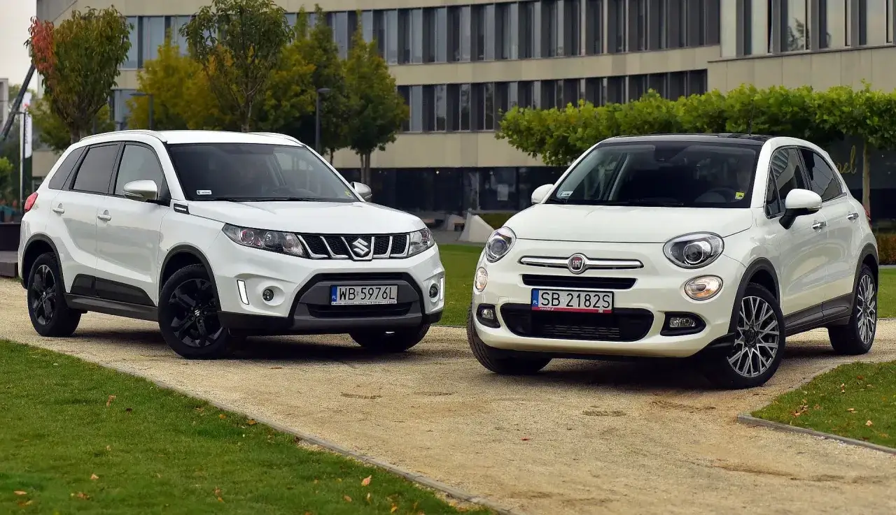 Dwa białe, małe SUV-y, idealne jako mały SUV dla żony. Suzuki Vitara i Fiat 500X stoją obok siebie.