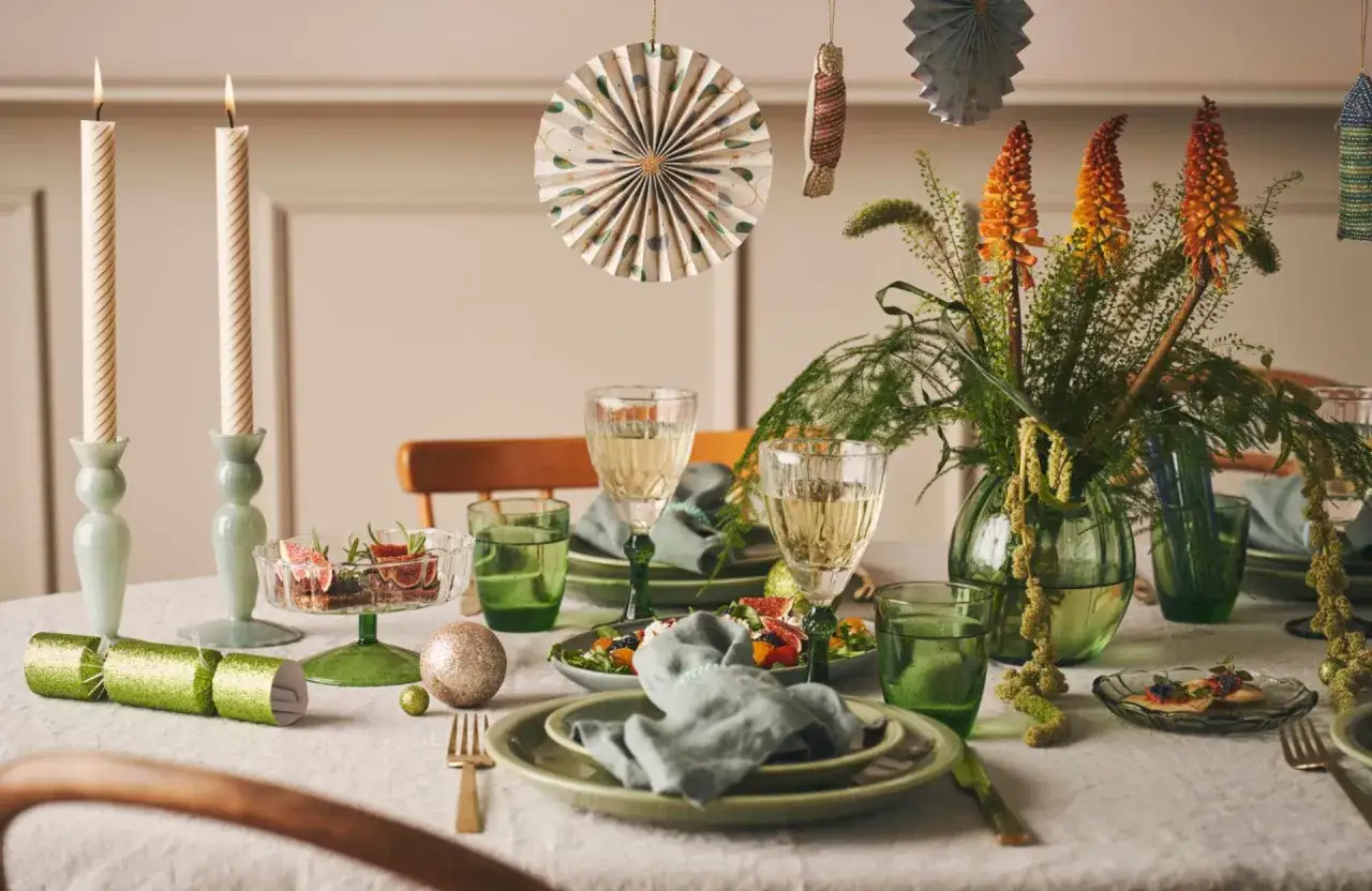 Table dress&eacute;e pour une f&ecirc;te familiale : bougies, fleurs, vaisselle verte et d&eacute;corations festives.