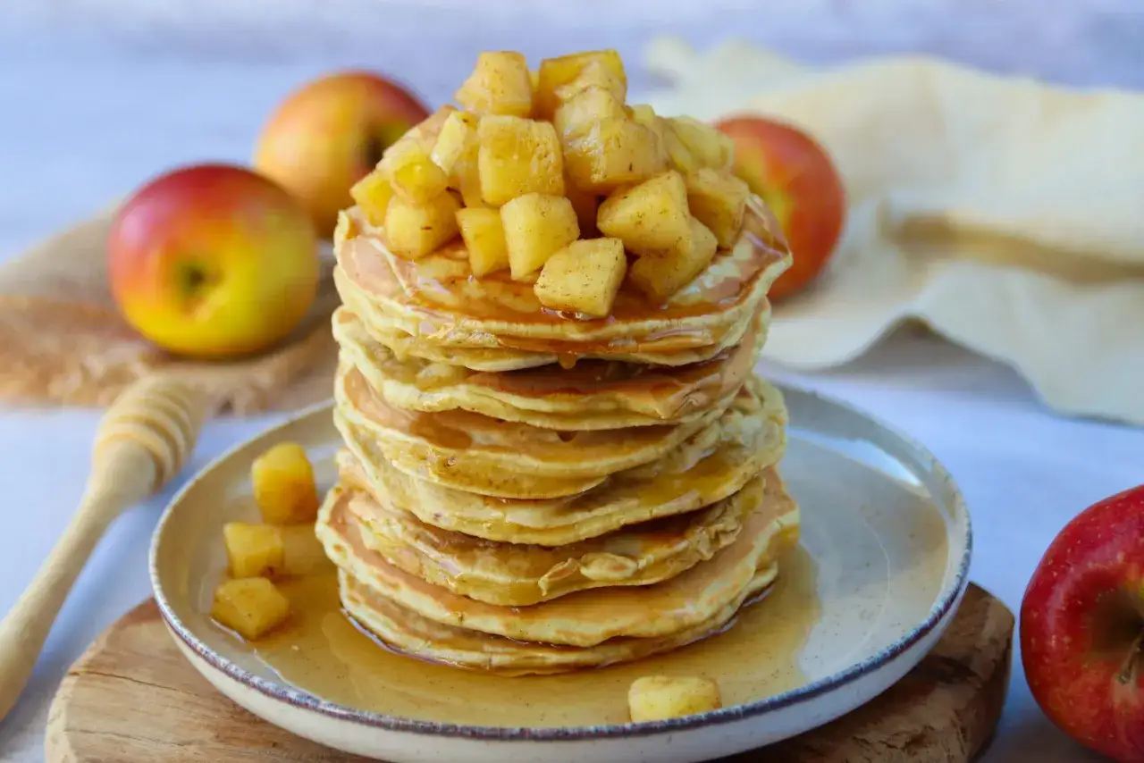 Pile de pancakes g&eacute;n&eacute;reuse, napp&eacute;e de sirop et garnie de morceaux de pomme caram&eacute;lis&eacute;e. Un d&eacute;lice pour le petit-d&eacute;jeuner.